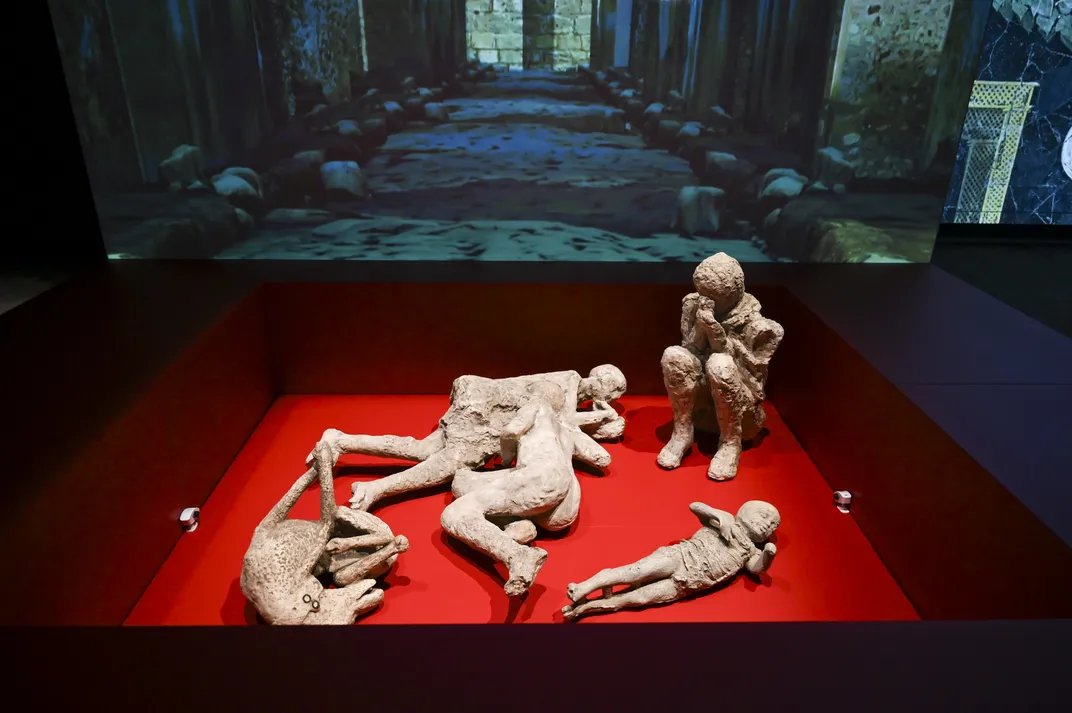 Casts of human figures against a red backdrop