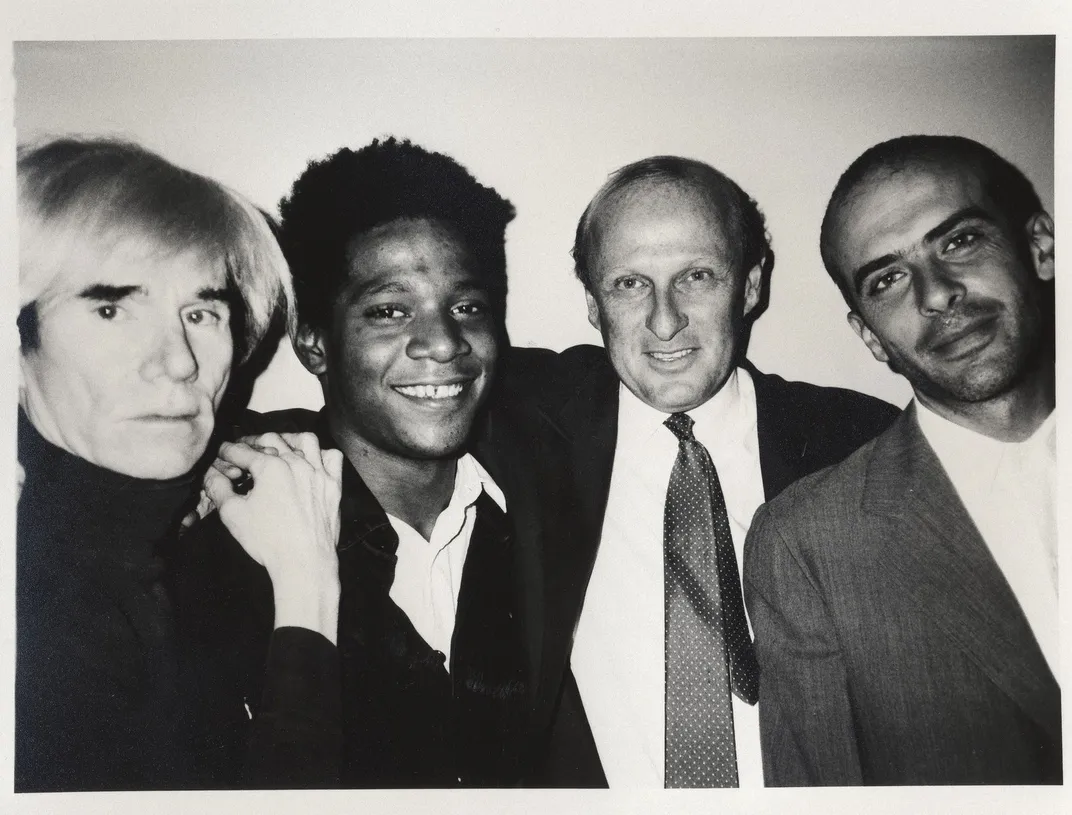 Warhol, Basquiat, Bischofberger and another man pose and smile together in a black and white image