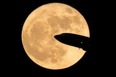 An aircraft takes off from Ronald Reagan National Airport, passing in front of the Moon as it rises above Washington D.C.