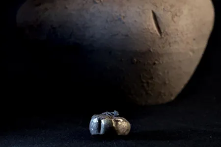 This gold earring found at an Iron Age archaeological site had been stashed inside a pottery jar, which sits behind it.