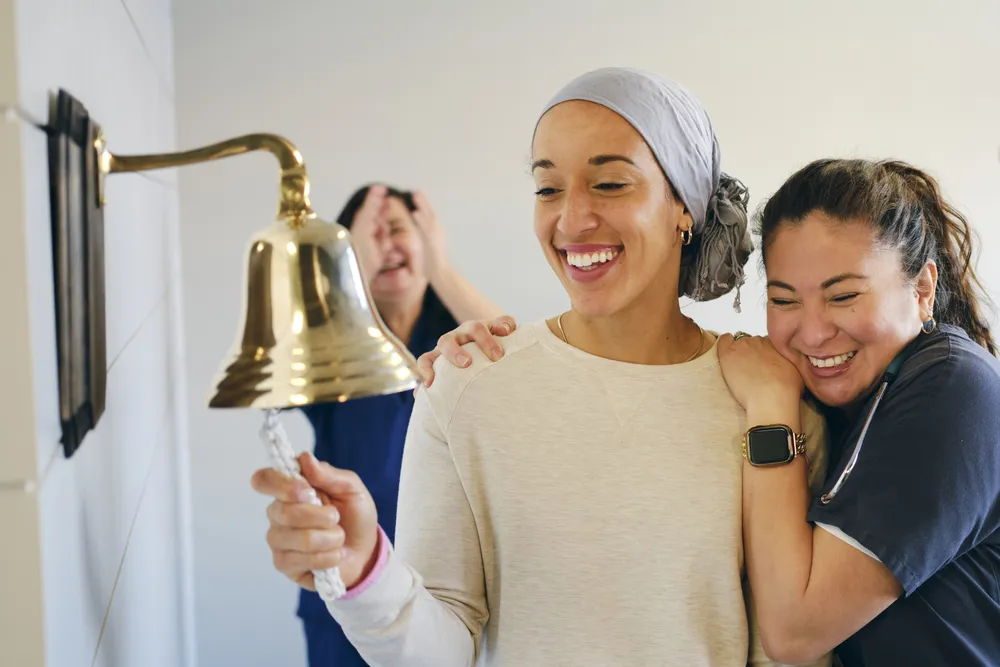 a woman rings a bell with nurses celebrating