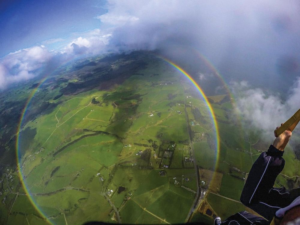 circular rainbow over green fields