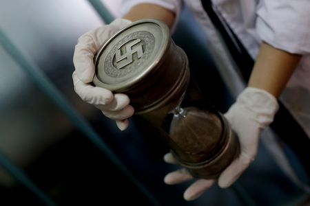 A member of the federal police holds an hourglass with Nazi markings, one of the 75 Nazi artifacts seized from an Argentinian house this June.
