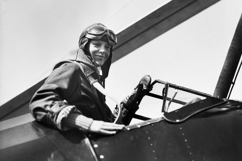 Amelia Earhart in a plane, wearing her flying cap