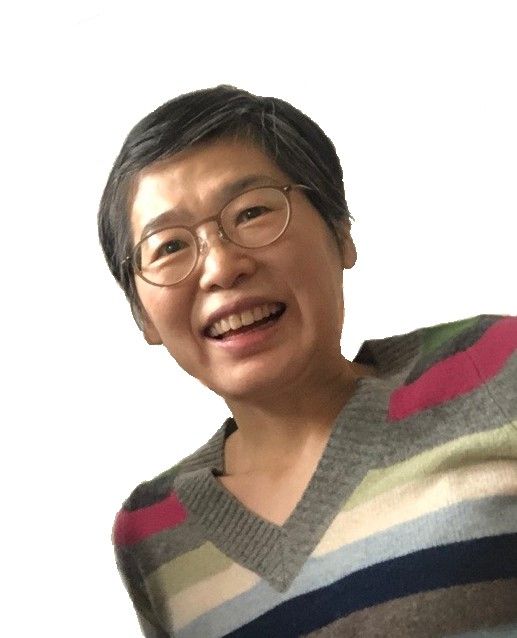 Jeong Ju Lee, a Korean American artist, smiles while wearing a striped, colored sweater