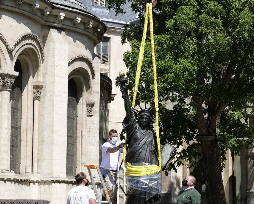 Workers remove a Statue of Liberty replica from its plinth