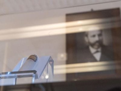A picture of Friedrich Miescher hangs behind a test tube with isolated nucleic acid from salmon sperm from the original holdings in the museum of the University of Tübingen.