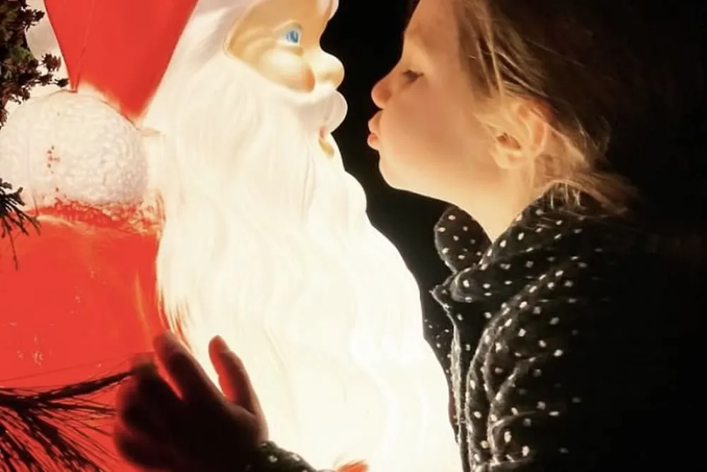 A young girl kiss a Santa Claus statue