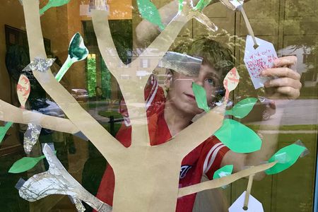 A boy adds a wish for the health of delivery workers during the 2020 pandemic. This  paper wish tree is inspired by artist Yoko Ono’s Wish Tree for Washington, on view at the Hirshhorn Museum’s Sculpture Garden.