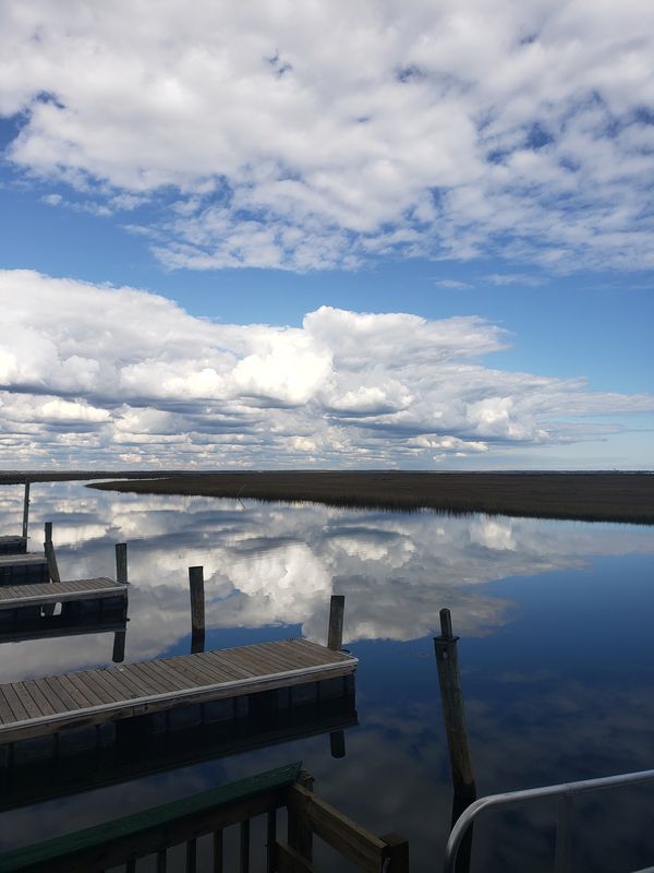Clouds reflection on a dock lined bay thumbnail