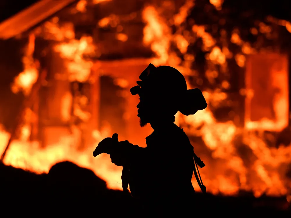 An inmate firefighter monitors flames as a house burns in the Napa wine region of California on October 9, 2017