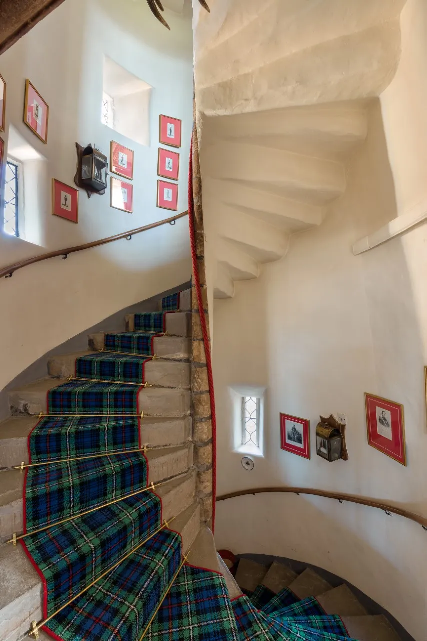 spiral staircase with plaid runner rolled over it
