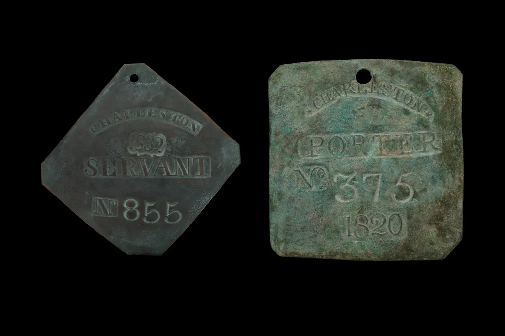 Two old metal badges next to each other against a black background