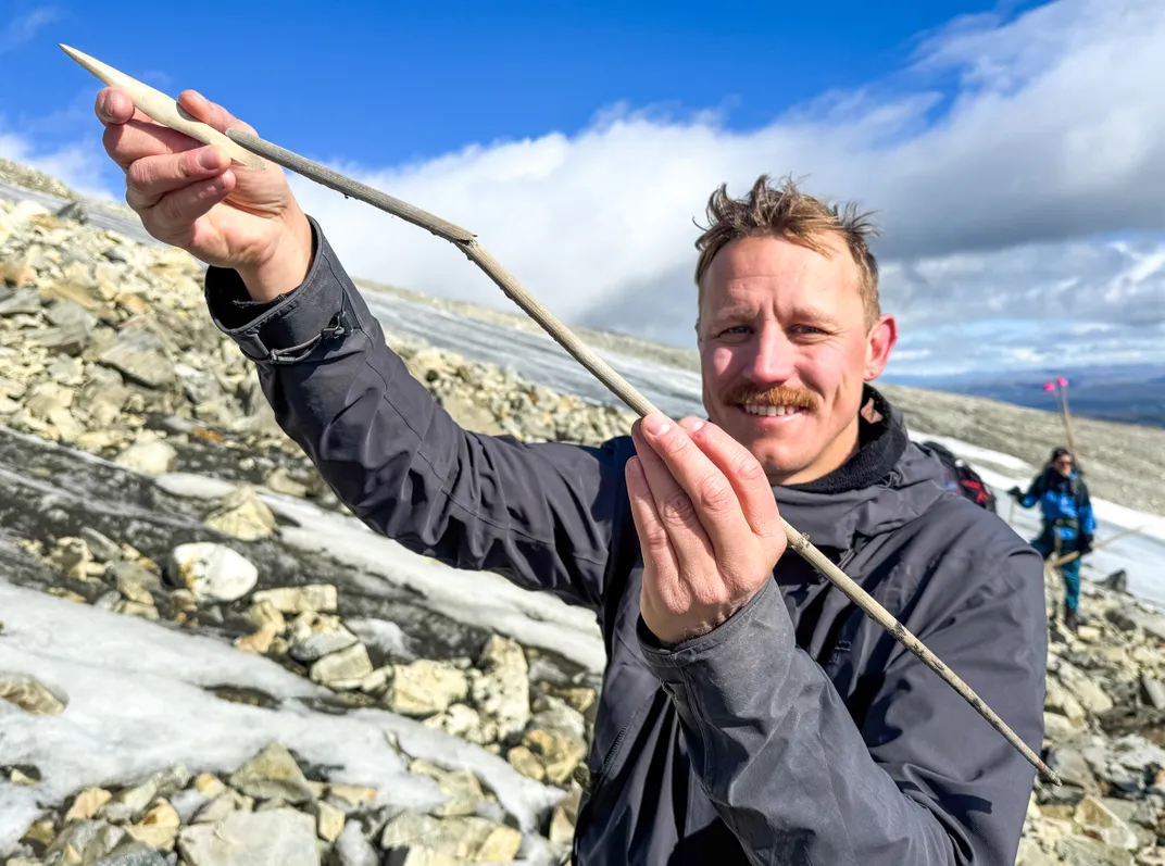 A man holding up an arrow with a wooden shaft
