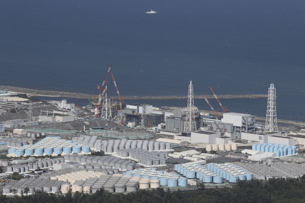 rows of blue, white and grey tanks next to the coast