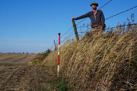 Isaac Larsen, a geosciences expert at UMass Amherst, stands near a drop-off that seperates native remnant prairie from farmland in Iowa. Reseachers found that farmed fields were more than a foot lower than the prairie on average.&nbsp;
