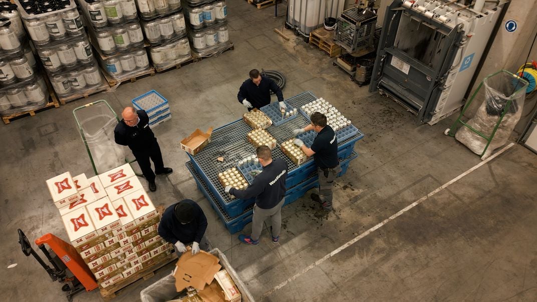 Workers pour out cans