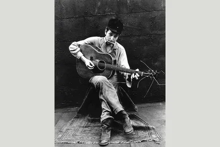 John Cohen photographs a young Bob Dylan playing his guitar and harmonica in New York City in 1962. 