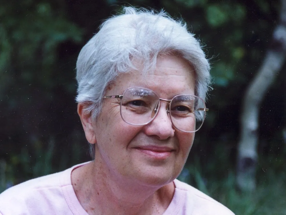 Vera Rubin in front of a green wooded area.