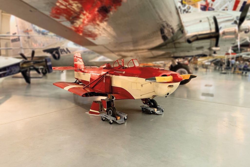 a red vintage airplane sits in an hanger