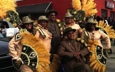Members of a New Orleans social aid and pleasure club sport stylish and costly outfits and masquerade regalia. Organizations like these walk together in funerals and parades, such as the famous New Orleans Mardi Gras parade.