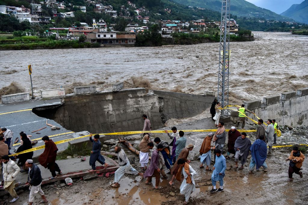 People surrounding a street damaged by flooding