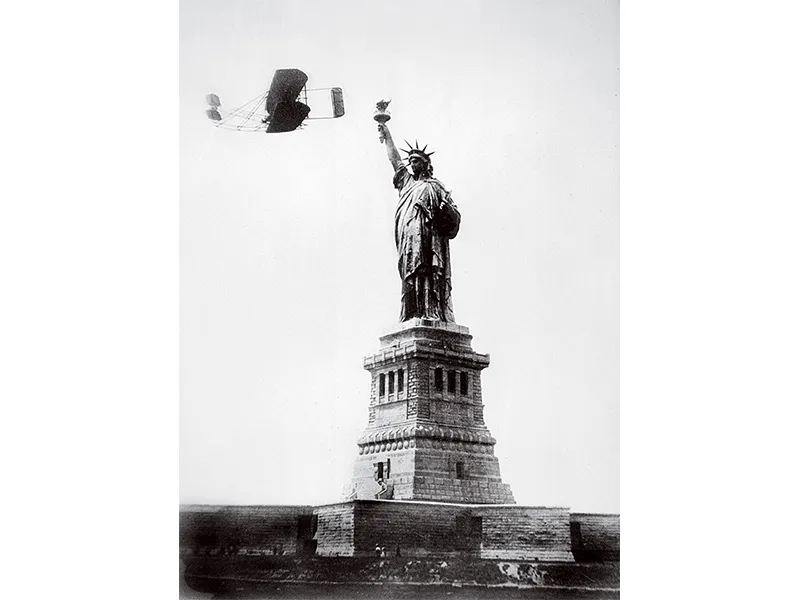 Wright plane passing Statue of Liberty