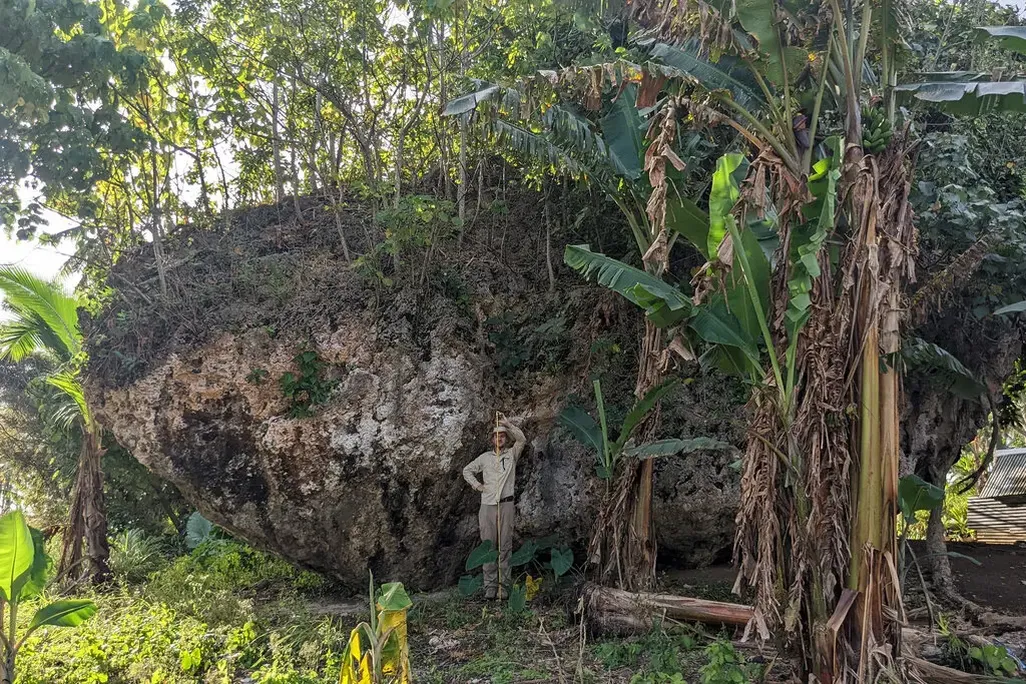 Man standing in front of large boulder