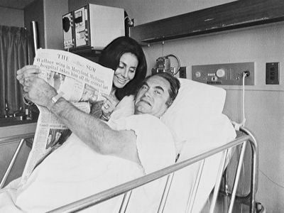 After his shooting, a hospitalized Wallace holds up a newspaper touting his victories in the Maryland and Michigan Democratic presidential primaries.