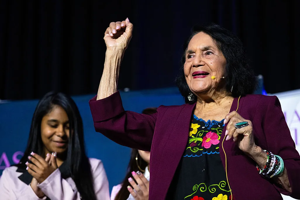 A woman with dark hair with her hand raised above her head