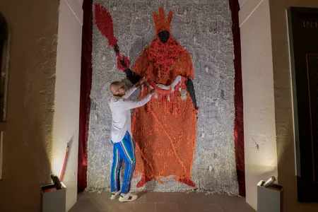 Artist Victor Ehikhamenor posing with his work, Still Standing,&nbsp;a mixed-media depiction of a Benin ruler.
