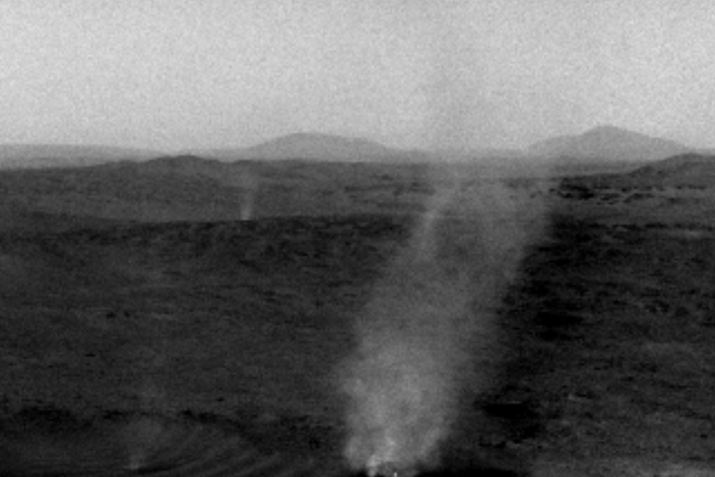 This screenshot from a video made of images taken by NASA’s Perseverance Mars rover showcases the larger dust devil on the right about to consume the smaller, fainter dust devil on the left.