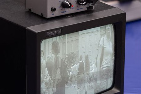 A small black and white tv monitor displays a fuzzy image on the screen. On top of it sits a box with nobs.