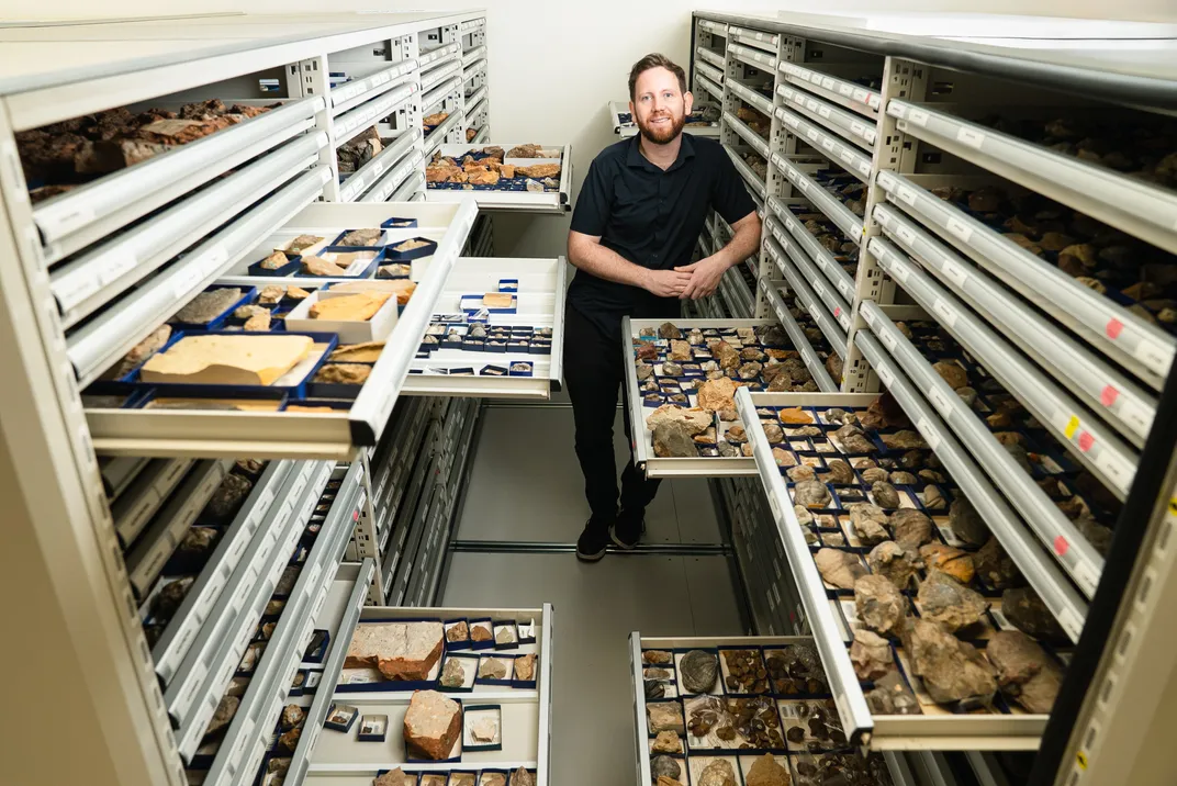 A man standing among drawers of fossils