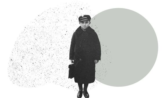 A boy in a long wool coat and hat holds a small case
