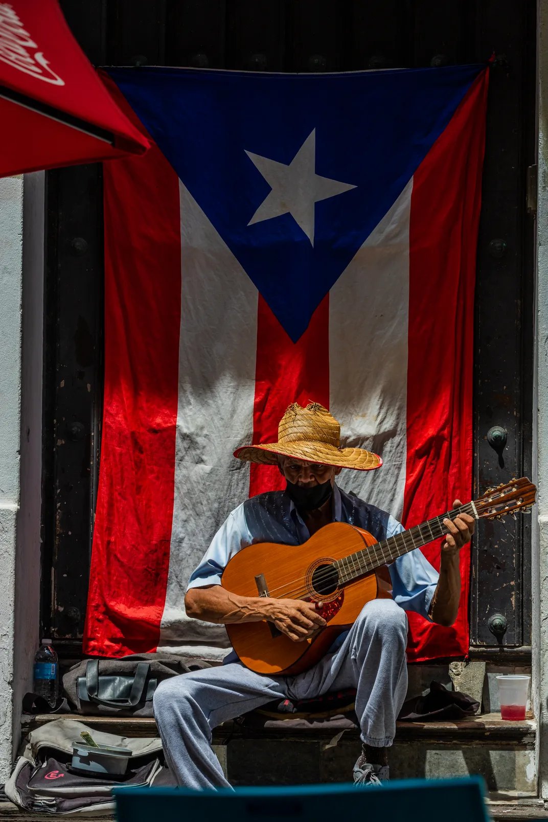 a man plays guitar in front of the flag of Puerto Rico