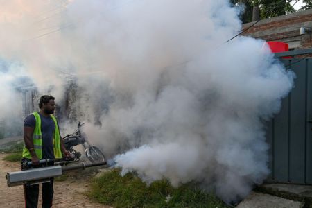 In residential district of Lahore, a health worker fumigates to kill off mosquito larvae to combat the spread of dengue.