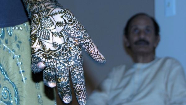 An Indian wedding. The bride and women close to her have their hands decorated with henna paste. thumbnail