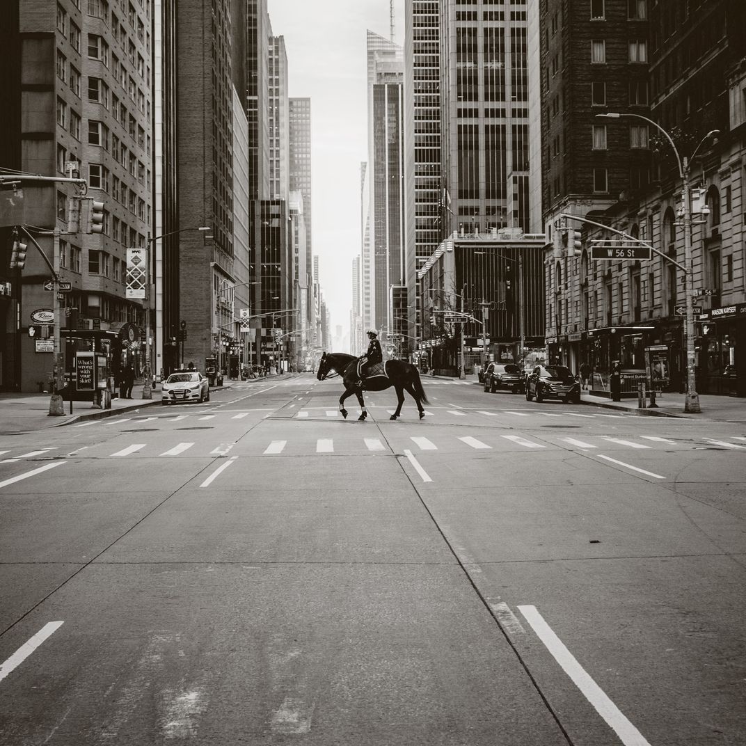 a mounted police officer rides through a deserted Manhattan