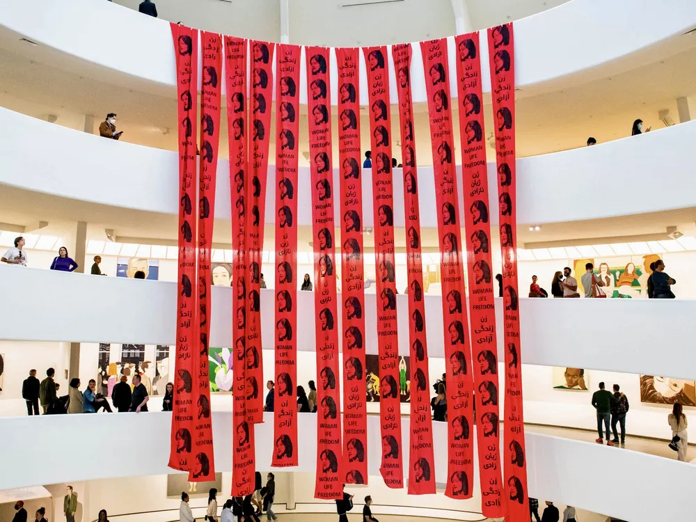 Red banners with Mahsa Amini’s face cover the Guggenheim spiral in anonymous protest action
