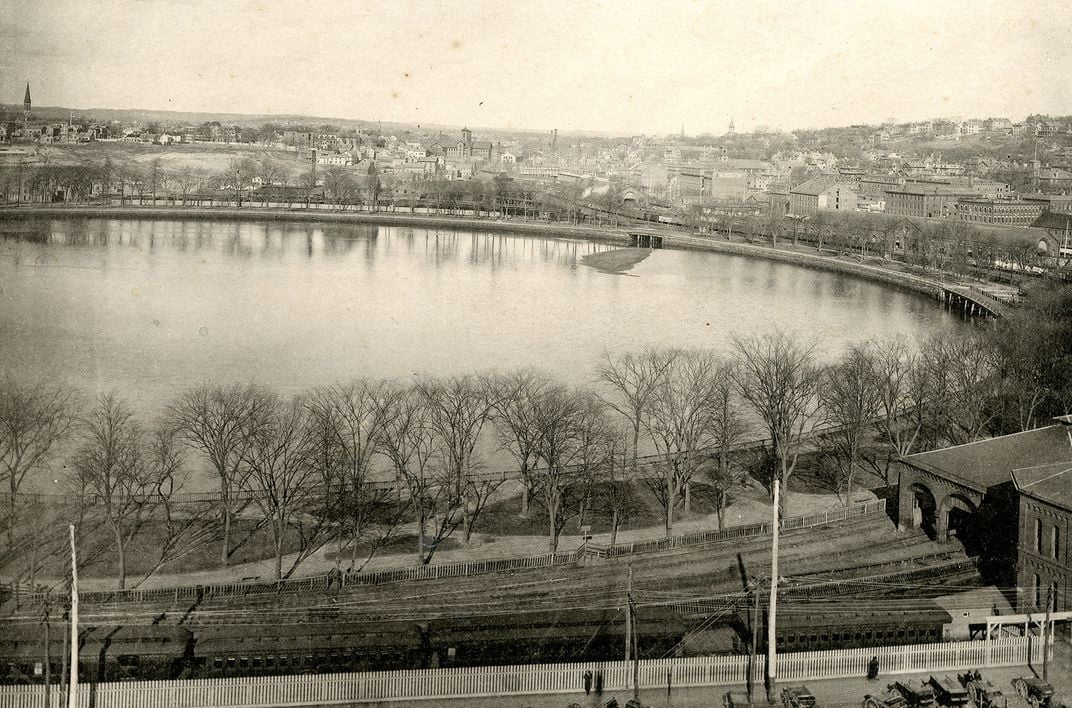 Rooftop view of Providence from City Hall, looking north over railroad tracks, Providence Cove, and buildings in the distance.