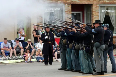 Civil War reenactors fire a salute in a public parade. 