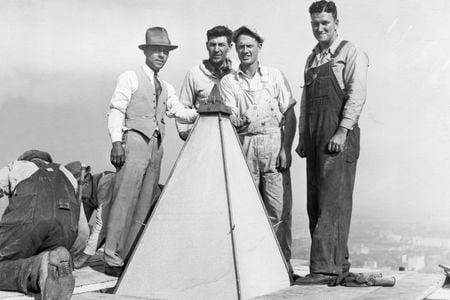 Man posing with construction workers at the top of the Washington Monument. The first restoration of the Monument began in 1934 as a Depression-era public works project. 