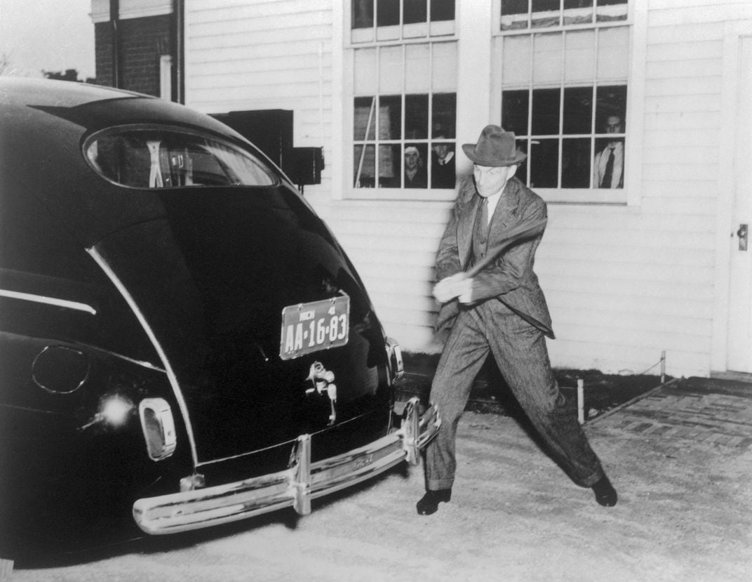 Henry Ford swinging an ax at the plastic trunk of his car