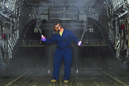 Staff Sergeant Daniel Fink sprays pesticide to rid the cargo hold of a C-17 Globemaster III of any Zika-carrying mosquitoes that may have stowed away.