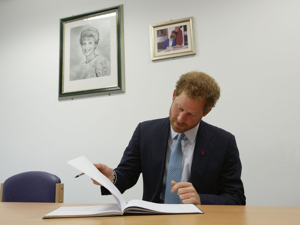 Prince Harry signs the visitors book during a visit to Mildmay hospital, a dedicated HIV hospital.