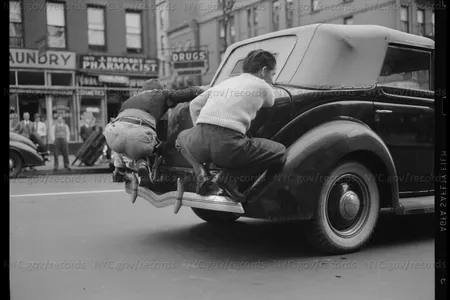 Men riding on the back of a car, 1940.