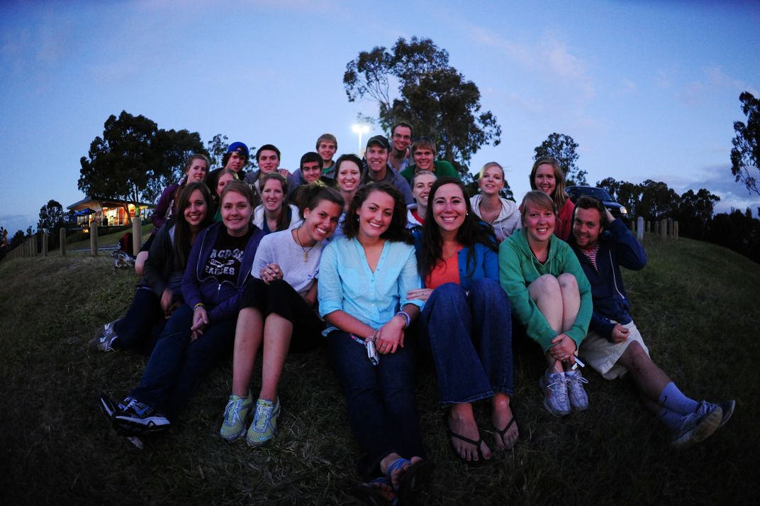 The group of young people facing the sunset singing in the top of the ...