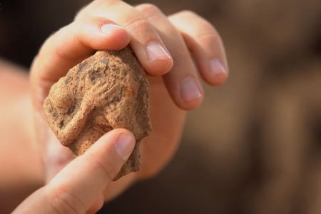 The researchers found a statuette of a woman holding a musical instrument that appears to be a drum.