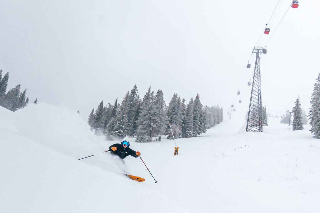 Person skiing on snow with gondola in the background